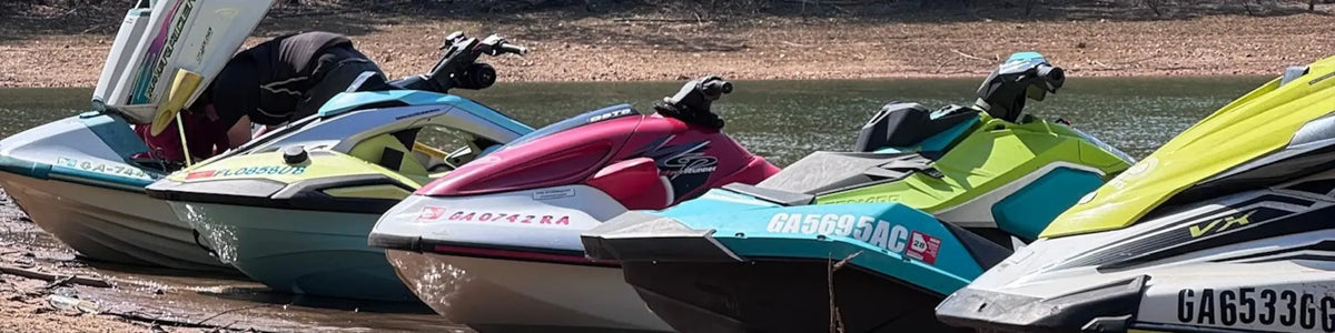 Personal watercraft lined up at the water's edge
